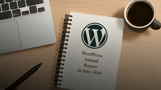 وردپرس در ایران- نمای مینیمالیستی از یک میز کاری مدرن با نور نرم شامل یک دفترچه فنری سفید با لوگوی وردپرس، لپ‌تاپ نقره‌ای، فنجان قهوه مشکی و قلم مشکی روی سطح چوبی روشن